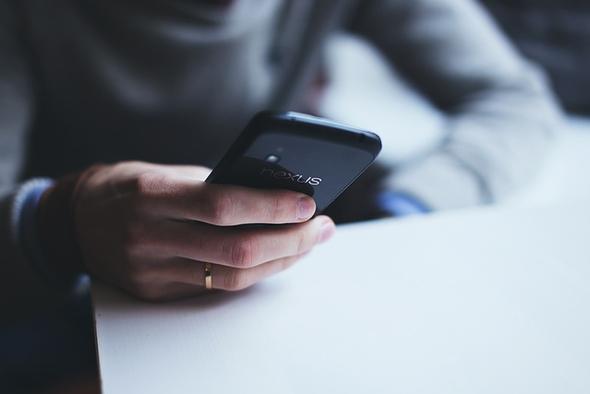 a close up image of a person holding a mobile phone on the go. 