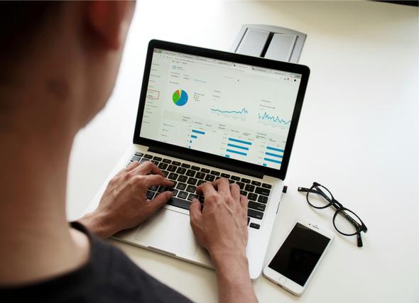 A person analyzing financial data on a laptop screen, displaying charts, graphs, and key metrics
