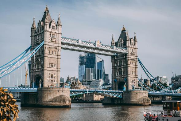 Tower Bridge stands over the River Thames with modern London skyscrapers in the background, representing the blend of tradition and regulation in the city.